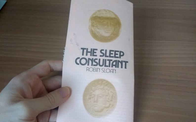 Adam Westbrook holding a copy of &ldquo;The Sleep Consultant&rdquo; by Robin Sloan