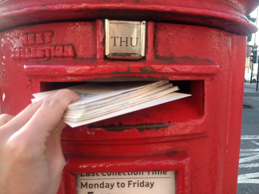 Adam Westbrook posts hand drawn postcards into a British letterbox