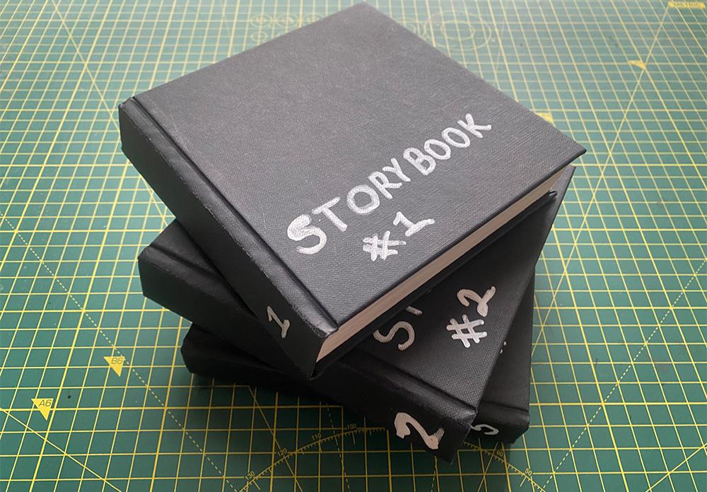 A photograph of three filled sketchbooks stacked on top of each other